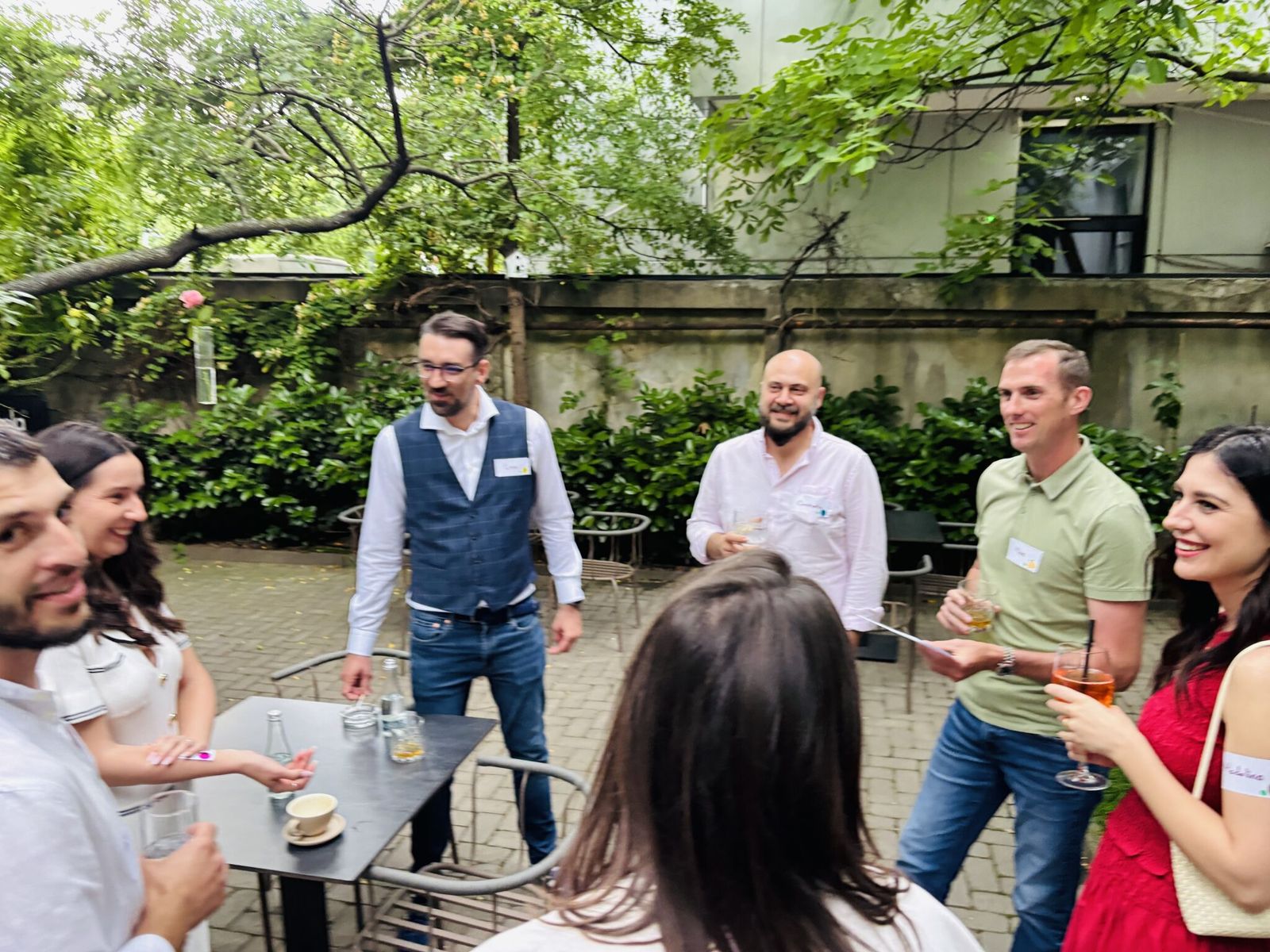 Guests laughing over drinks in the A46 courtyard at a 3rd Space Bucharest event