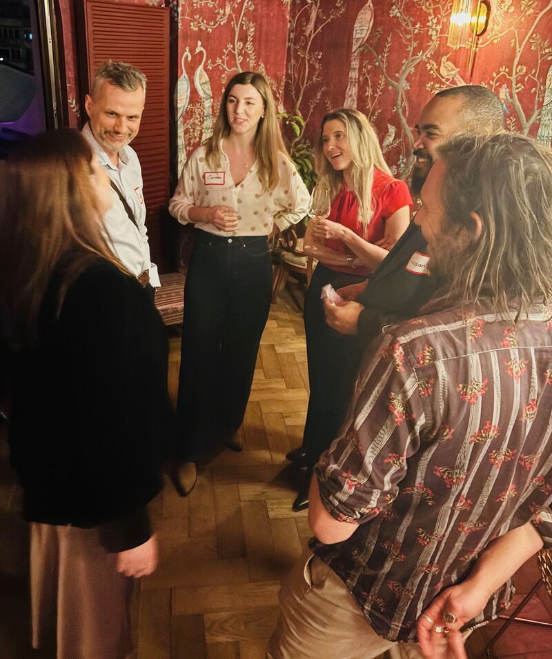 Guests laughing together in a red, bird-patterned room at a 3rd Space Bucharest social