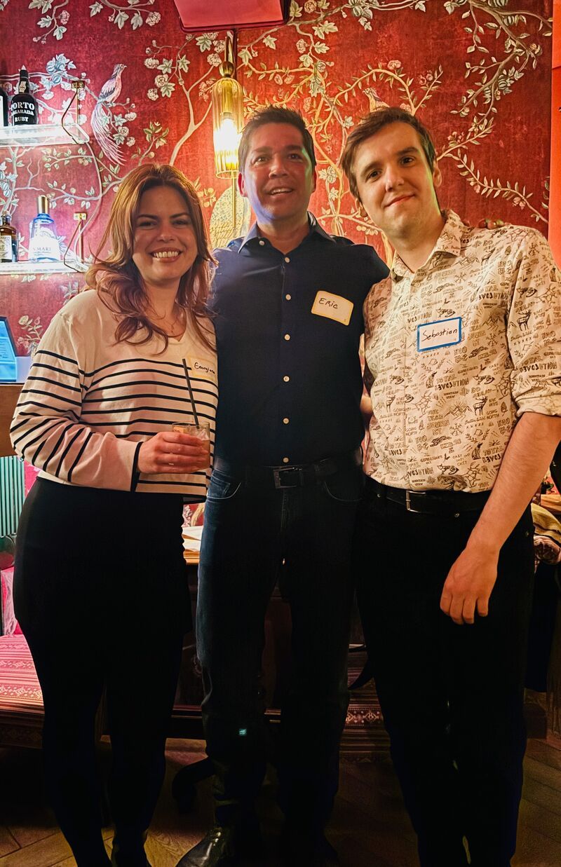 Eric Melchor with two guests in front of a red floral mural in Bucharest