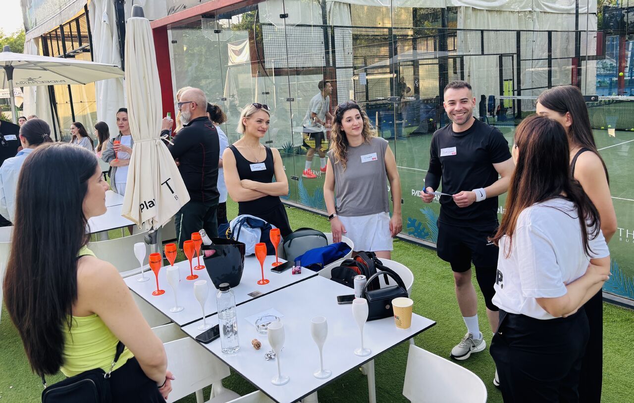 Guests chatting over prosecco beside the padel courts at a 3rd Space Bucharest social