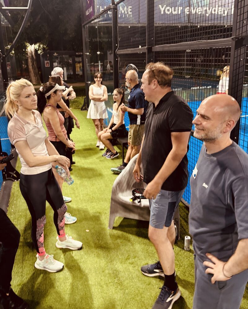 Guests talking courtside during the evening padel social