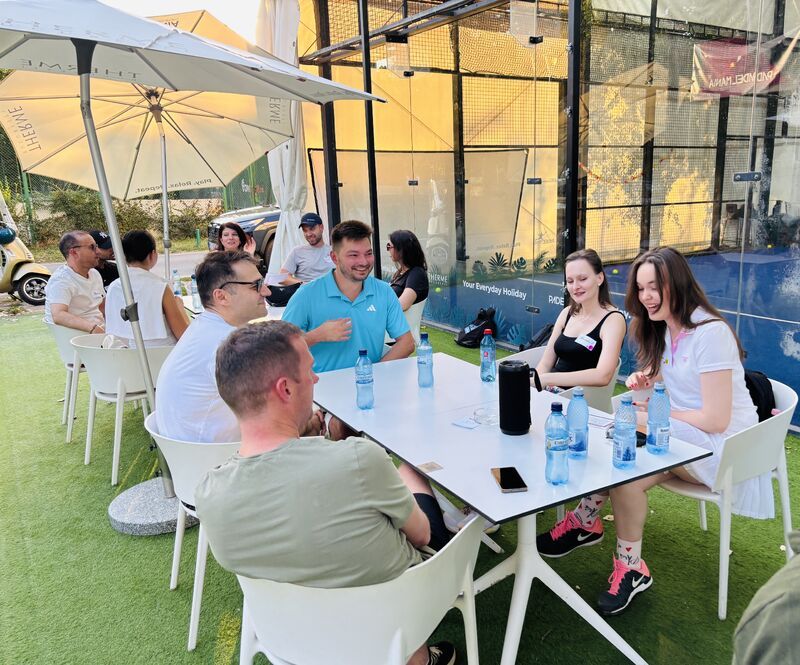 Guests chatting courtside at the August padel social