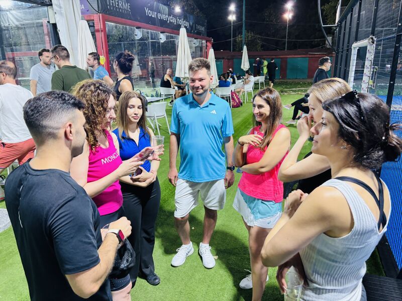 Guests talking between matches on the padel court at night