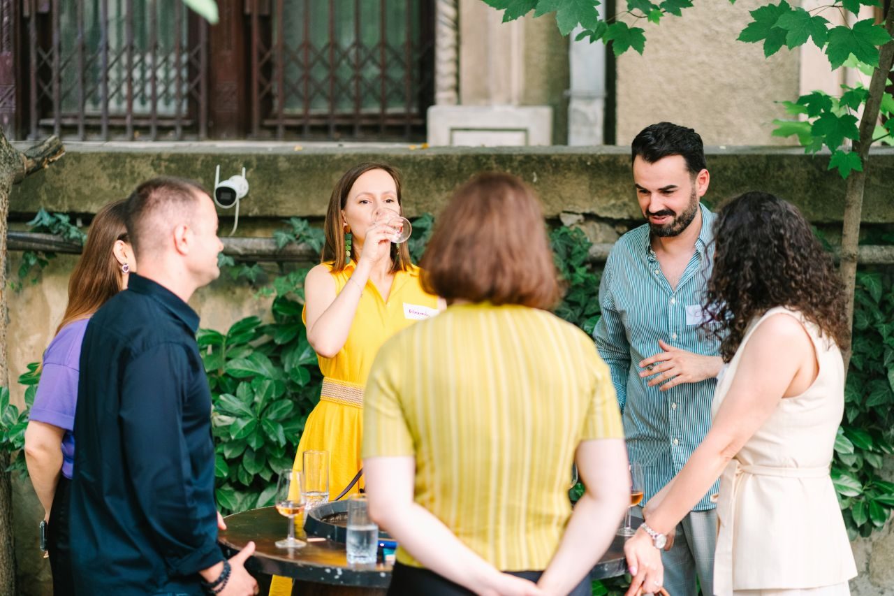 Three guests laughing together over a glass of wine at the 3rd Space Bucharest wine social