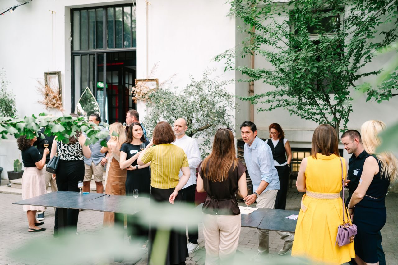Guests spread across the courtyard in conversation at the Romanian wine tasting in Bucharest
