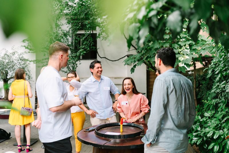 Guests laughing around a barrel table at the 3rd Space Bucharest wine tasting