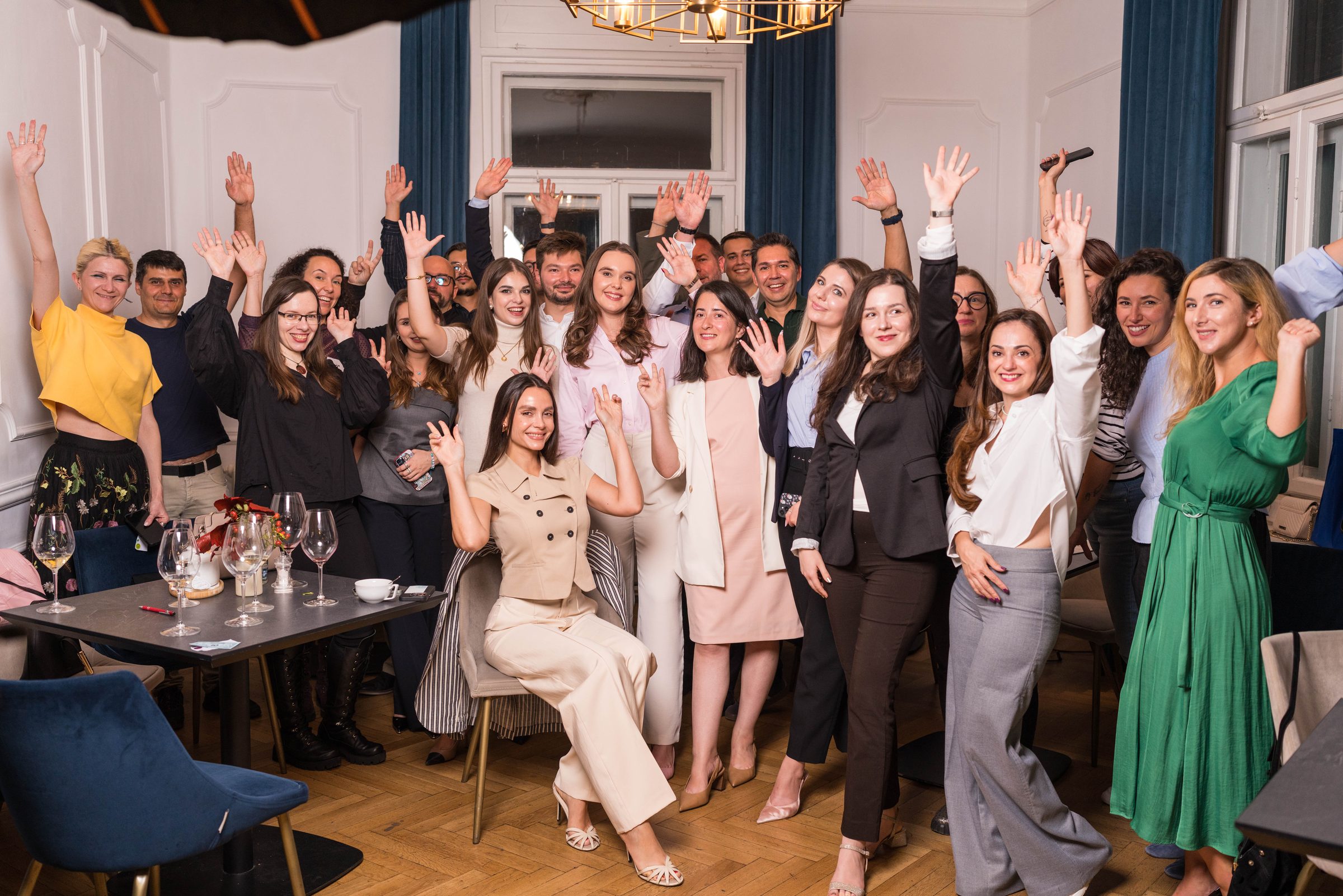 The 3rd Space Bucharest community with their hands up at a cocktail evening in Bucharest